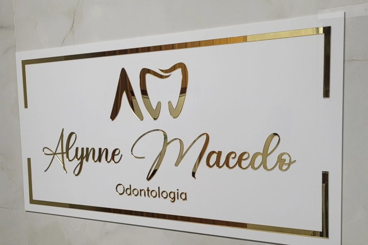 Placa dourada com o nome Alynne Macedo Odontologia na parede do consultório